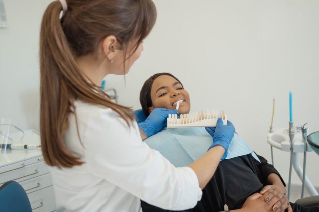 Patient undergoing dental shade matching at a clinic with a female dentist.